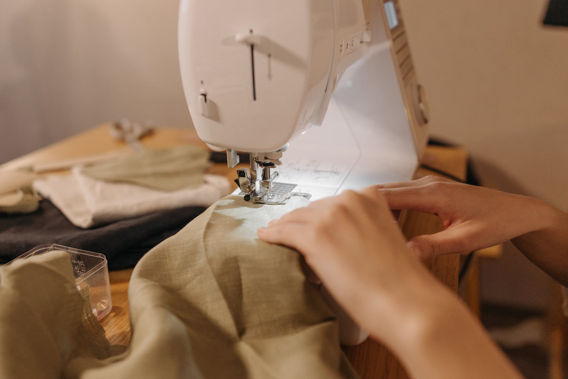 person sewing cloth on a sewing machine - attaching fabric label to finished garment made in China